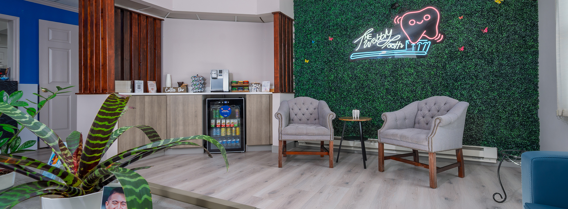 The image shows a living room with a wall-mounted television displaying a news broadcast featuring an anchor discussing a story, with a colorful backdrop of a cityscape and a heart logo.